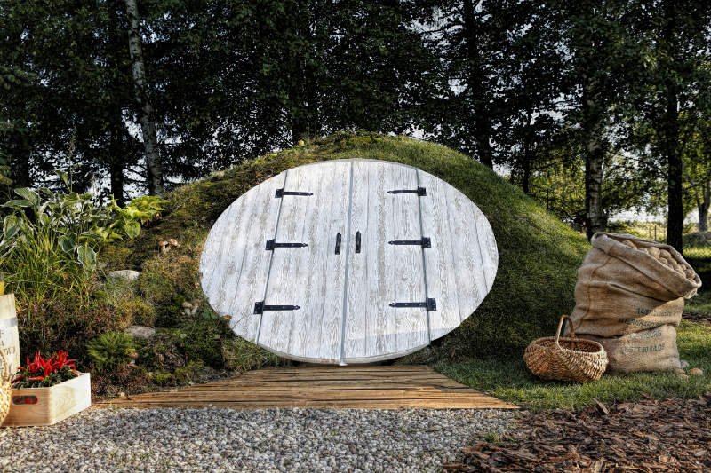 coolcubby Erdkeller mit weißer Haustür als Highlight des Gartens in einen Hügel eingebaut